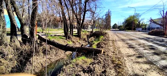 Vista de la calle de tierra junto al canal de desagüe en Cipolletti