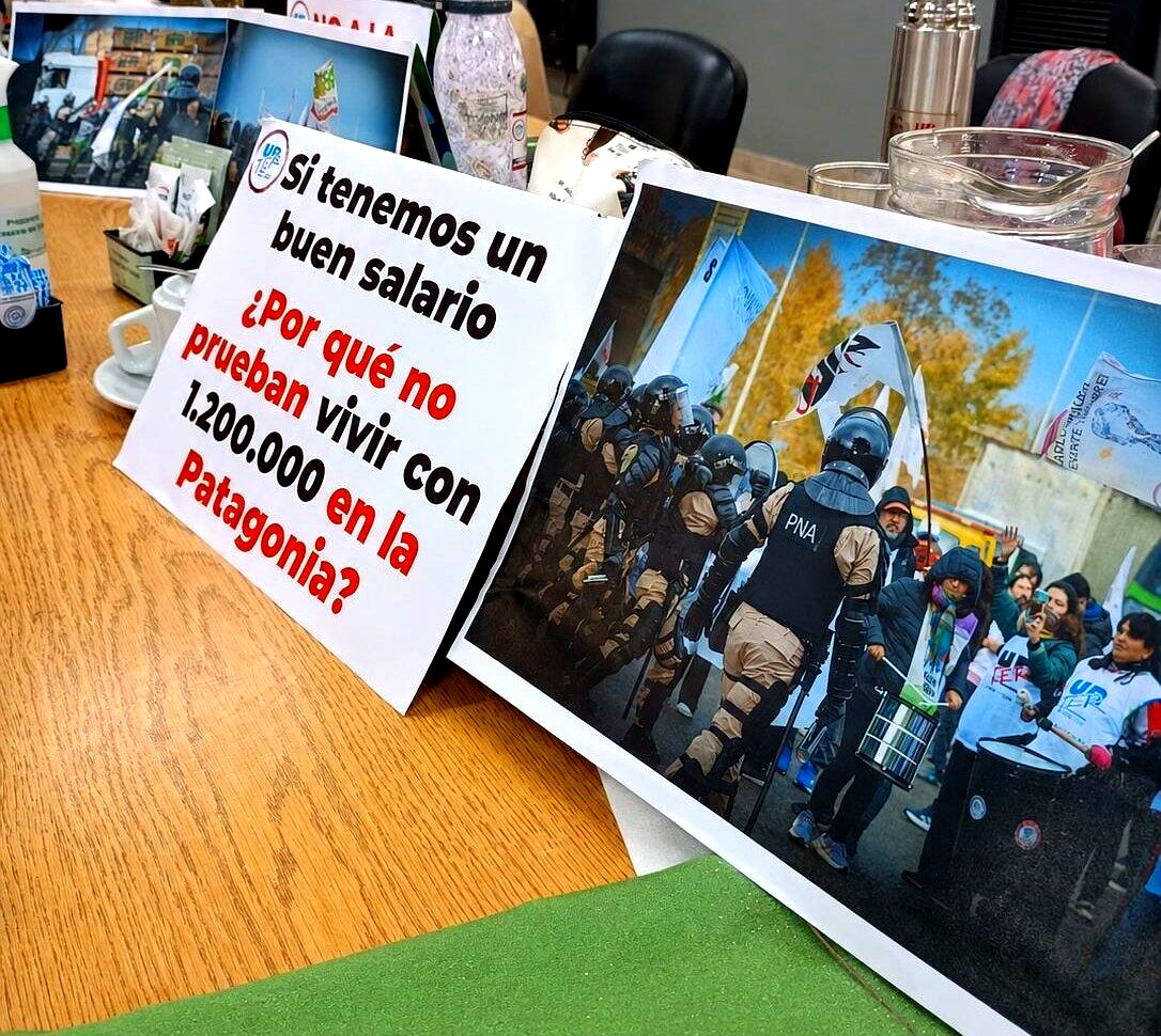 Carteles de reclamo salarial de trabajadores estatales en una mesa de negociación en Río Negro