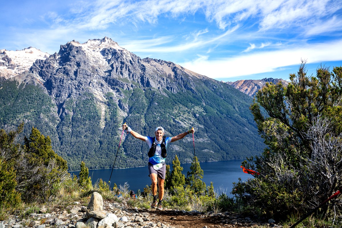 Ultra trail en Bariloche: un competidor festeja en un sendero frente a un lago